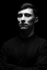 Fototapeta na wymiar Low key portrait of a man in black shirt in black and white.