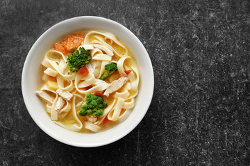 Chicken noodle soup in bowl on grey background