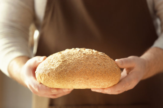 Male chef with loaf of bread, closeup