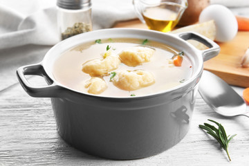Ceramic pan with delicious chicken and dumplings on light wooden table