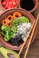 Sushi bowl with seaweed, avocado,  radishes, cucumber and black sesame seeds.