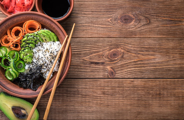 Fototapeta na wymiar Sushi bowl with seaweed, avocado, radishes, cucumber and black sesame seeds.