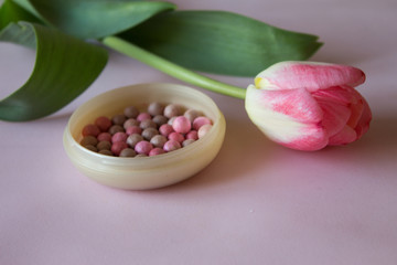 Pink cosmetic rouge with pink  tulip on the pink background