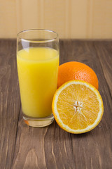 Fresh ripe orange and orange juice on a wooden background