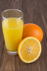 Fresh ripe orange and orange juice on a wooden background. Close up