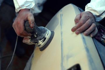 professional mechanic using a power buffer machine for cleaning the body of a car from scratches....