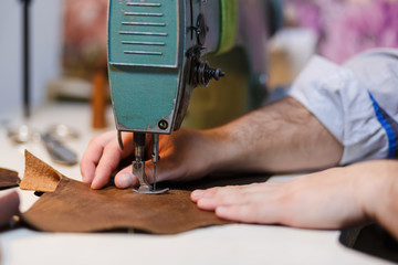 Tailoring process - men's hands behind sewing leather. Selective focus.