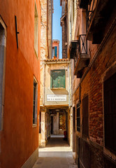 Fototapeta na wymiar Narrow street among old colorful brick houses in Venice. Veneto, Italy