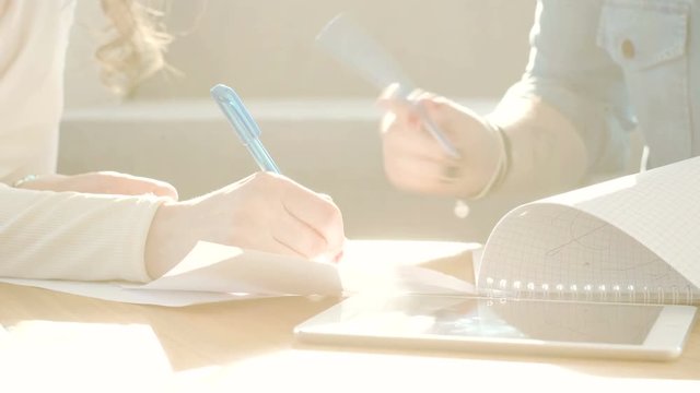 gestures and movements of female hands with pens during discussion working over solving business tasks with papers and documents and making notes on the desk in the office during bright sunny day