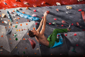 Obraz na płótnie Canvas man practicing rock-climbing on a rock wall indoors