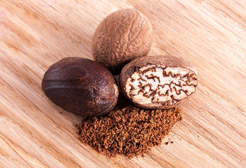 Macro shot of few nutmeg on wood background. 