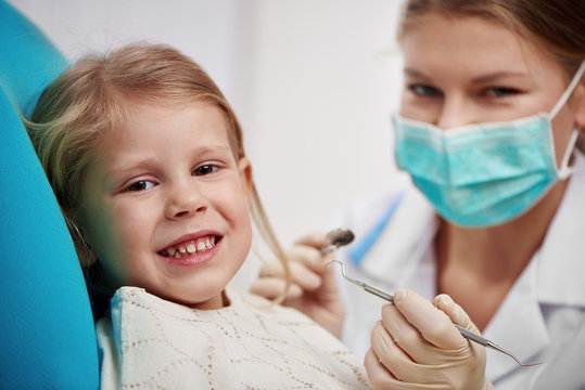 Small girl curing teeth in dentist office. Concept of milk tooth inspection and treatment.