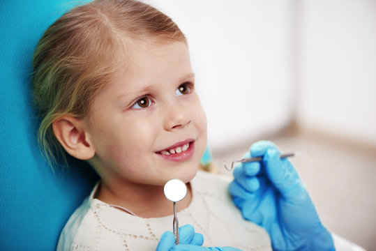 Cute child sitting on the chair in dentist office. Concept of teeth disease and examination. 