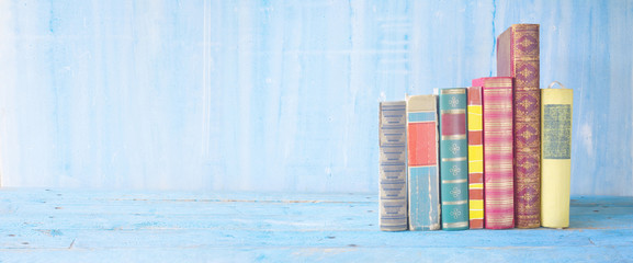 row of books on blue grungy background, panoramic, good copy space
