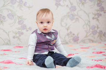 Cute happy little baby boy on bed in room