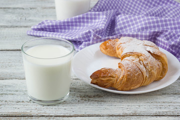 Croissant with milk on old wooden table for breakfast background.