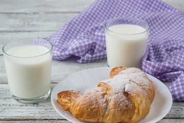 Croissant with milk on old wooden table for breakfast background.