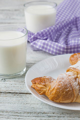 Croissant with milk on old wooden table for breakfast background.