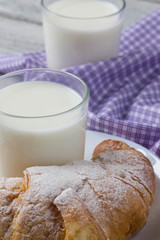 Croissant with milk on old wooden table for breakfast background.