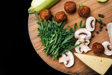 Vegetarian falafel and fresh green vegetables and mushrooms on a wooden board