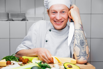 Man in a white cap cooking vegetables in the kitchen vegetarian. Cook.