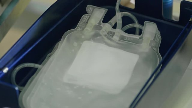 Closeup of placing plastic bag into tray during preparation for blood transfusion 