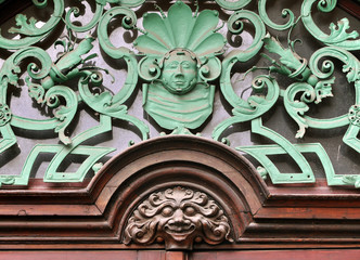 Detail of the entrance to the old building in Prague. Vintage decorations over the door based on curves shapes and stylized faces.