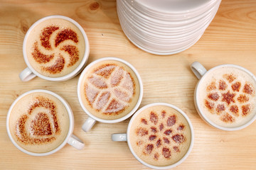 A lot of cups of coffee and a plate with a fire. coffee with milk. Drawing the foam milk on top.