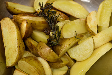 Potato slices fried in oil in a frying pan with rosemary