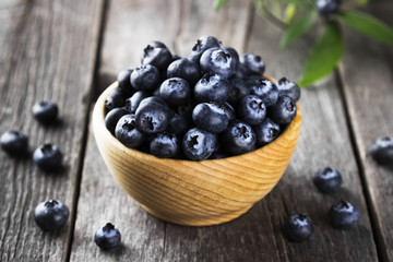 Blueberry in wooden bowl on a dark wooden background