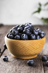 Blueberry in wooden bowl on a dark wooden background