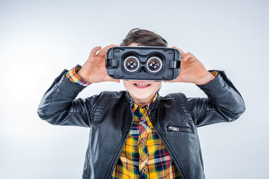 portrait of boy wearing virtual reality headset on grey