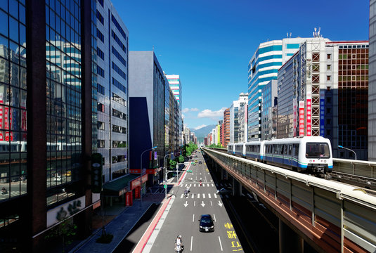 View of a train traveling on elevated tracks of Taipei Metro System between office towers under blue clear sky ~ View of MRT railways in Taipei, the capital city of Taiwan, on a beautiful sunny day