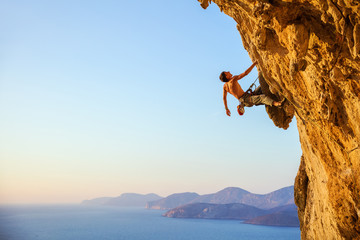 Rock climber on cliff at sunset