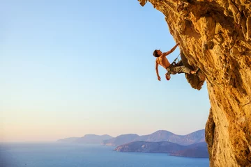Gordijnen Rock climber on cliff at sunset © Andrey Bandurenko
