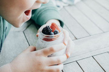 Boy eating Pudding with chia seeds, yogurt and fresh fruits: Strawberries, blueberries and...