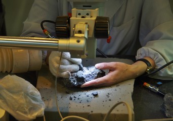 ラボで顕微鏡を見ながら作業する研究者