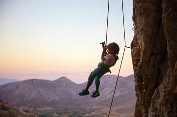 Little boy being lowered down while top rope climbing