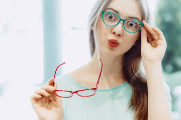 young woman trying on different pairs of eyeglasses - 141035847