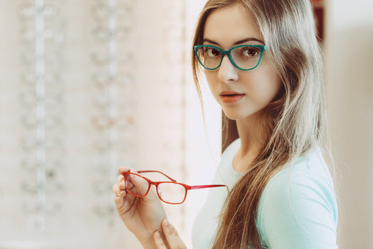 young woman trying on different pairs of eyeglasses
