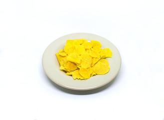 Plate with yellow corn snacks flakes on white background healthy breakfast snack lunch