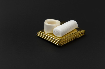 closeup of adhesive tape and elastic bandage on emergency blanket, isolated on black background