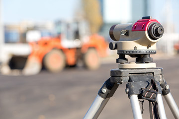 Land surveying equipment theodolite at construction site on wheel loader machine background