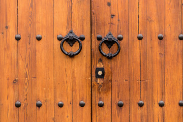 Fototapeta premium Ancient closed wooden gate with two door knocker rings