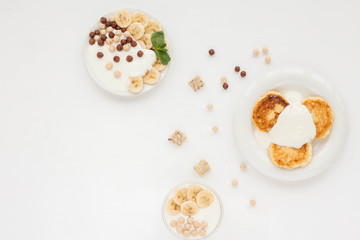 Dessert with yogurt, muesli, banana, pancake on white background. Flat lay