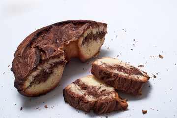 A piece of marble English cake with crumbs on a white background