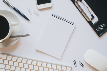 Office items on a white table. Clean Notepad in the middle