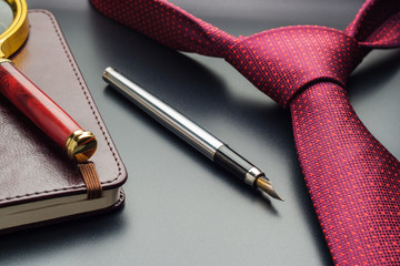 Male still life. A fountain pen with a notebook lies on a tie.