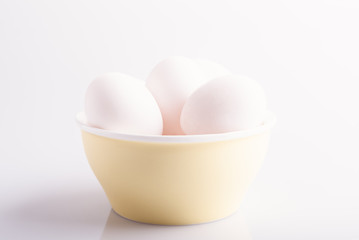 Bowl with white eggs on white background
