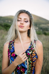 Naklejka premium beautiful dreamy blonde girl with blue eyes in a light turquoise dress lying on the stones